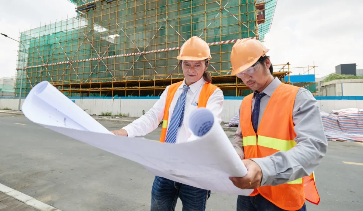 Construction professionals reviewing building plans while choosing the right construction software for project planning and collaboration.