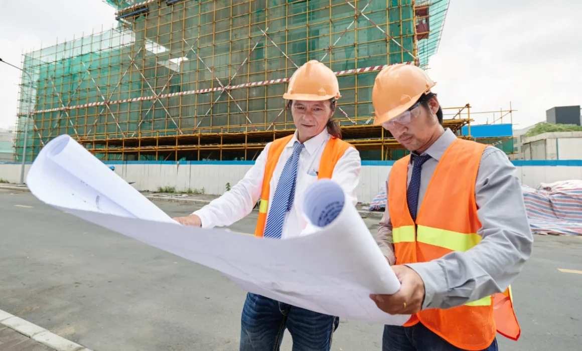 Construction professionals reviewing building plans while choosing the right construction software for project planning and collaboration.