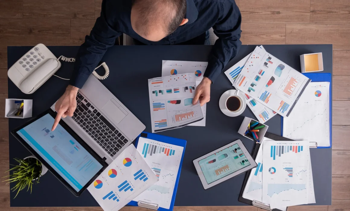Builder comparing construction software options using data reports on a laptop and tablet.