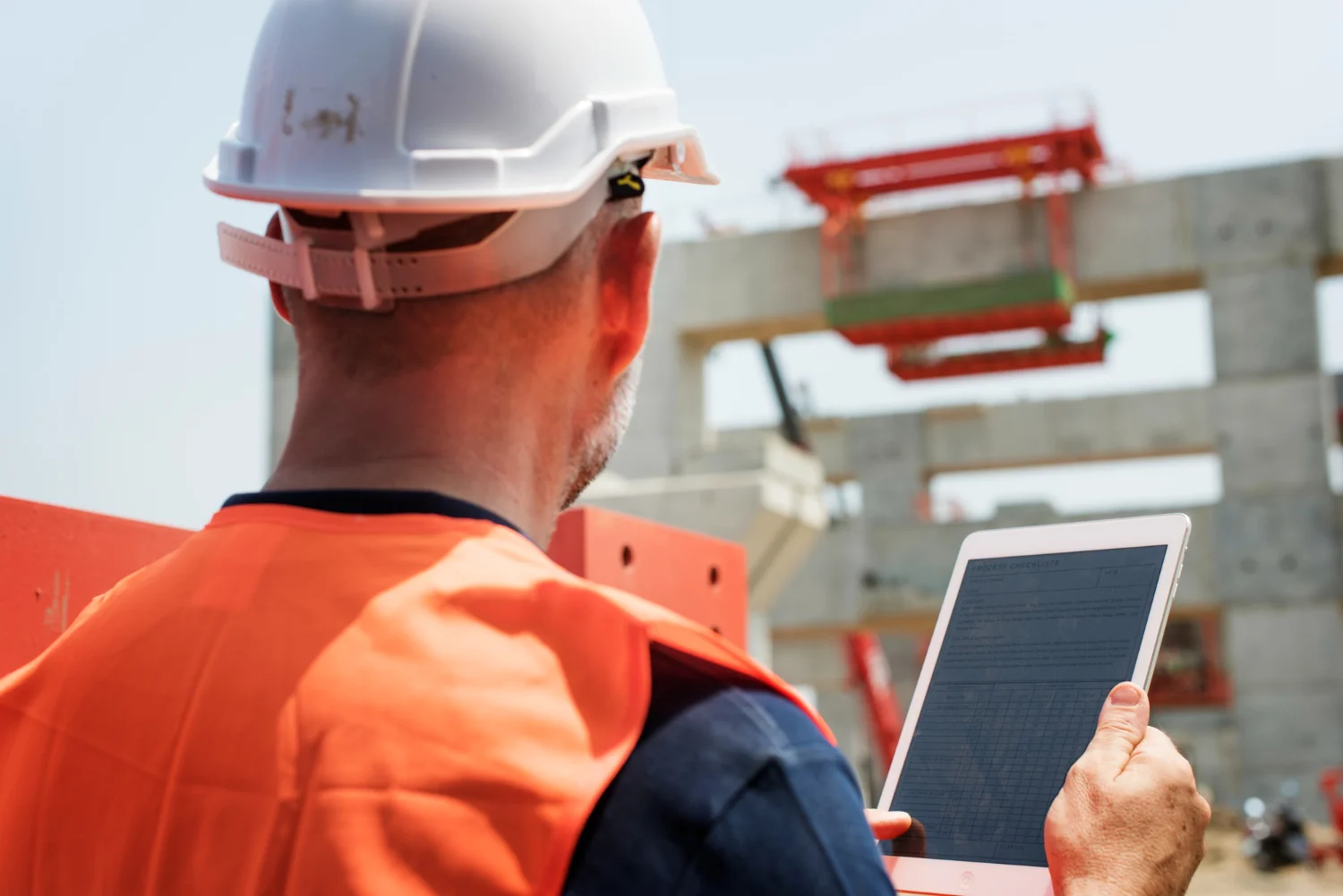 Site engineer filling a daily progress report format on a tablet at a construction site